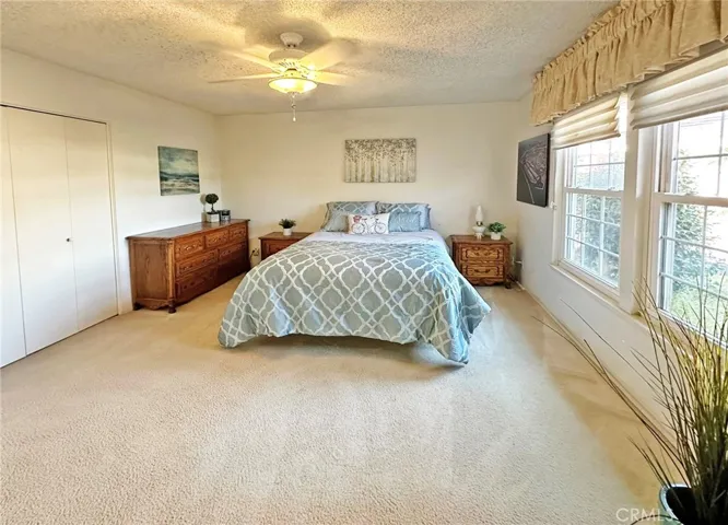 Primary Suite Bedroom has Ceiling Light Fan, dual Pane French Style Windows, Custom Window Shades, and 2 Closets