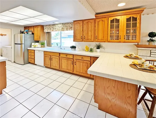 Bright Spacious Kitchen with Tile Flooring & Countertops, Breakfast Bar, and Beautiful Cabinetry
