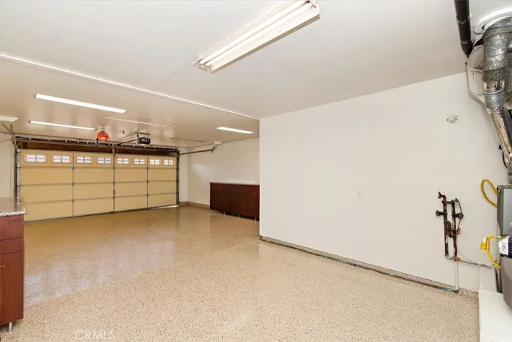 Upgraded tandem 3 car garage featuring a brand-new garage door opener, drywall finished, epoxy flooring, bonus storage cabinets and more storage space above the garage.