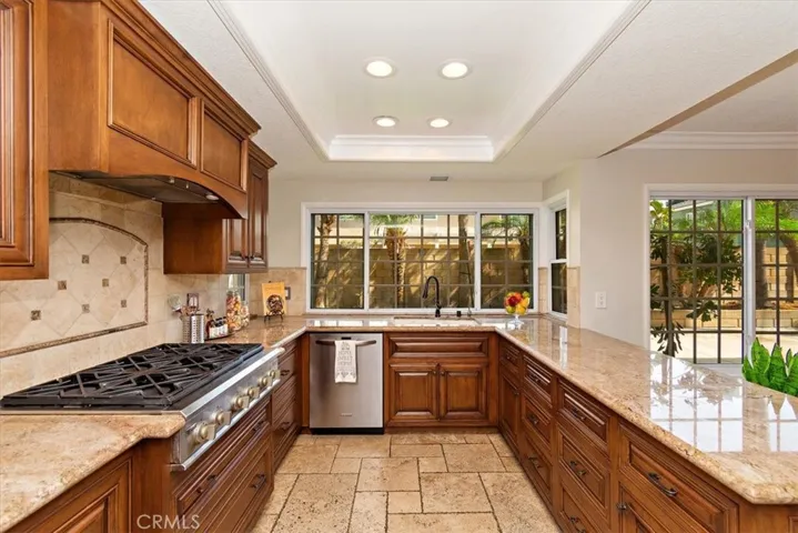 The magnificently upgraded gallery kitchen, featuring abundant custom-crafted cabinetry, spectacular granite countertops space, decorative tiled backsplash, a breakfast bar,6 burners gas range, double-deck ovens