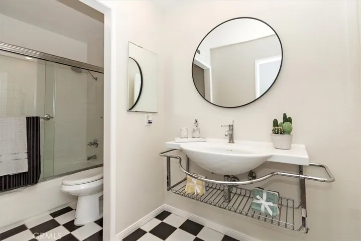 The upstairs hallway full bath is equally refined, with open vanity shelves, a sleek modern mirror, and striking black-and-white tile flooring.