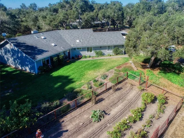 Main house with fenced veggie and flower garden in front.