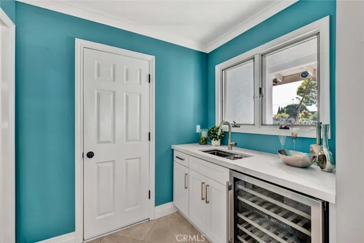 A well-equipped wet bar with a wine refrigerator, sink, and additional cabinetry adds the perfect touch for entertaining.