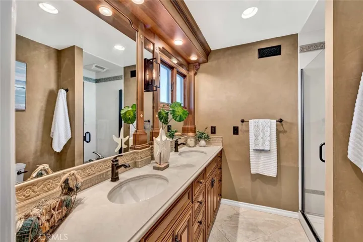 fully updated bathroom with custom cabinetry, dual sinks