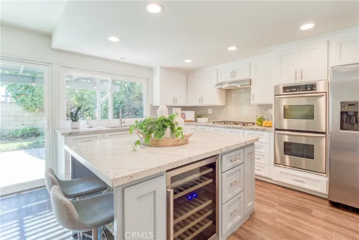 Quartz countertops, center island with built in wine refrigerator and microwave and an abundance of additional storage~