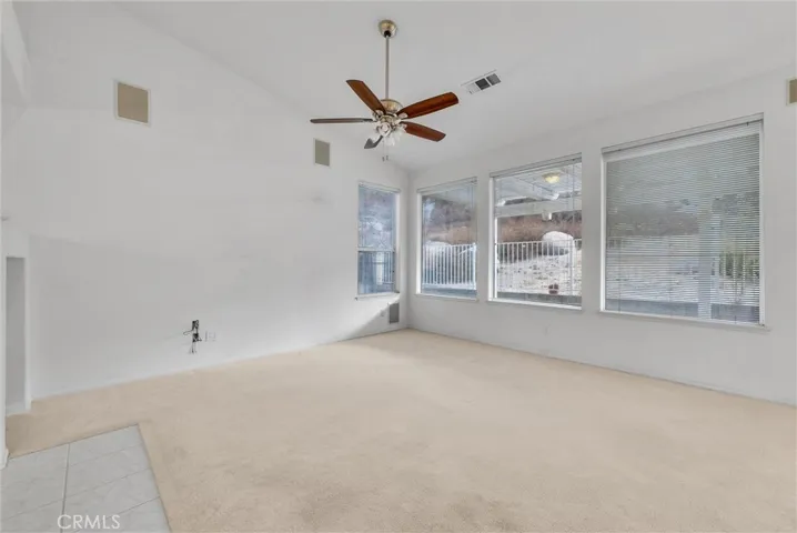 Large family room with ceiling fan and installed speakers.