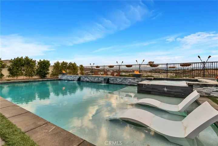 Resort like baja deck in pool, with spa, waterfalls, fire pit and forever views