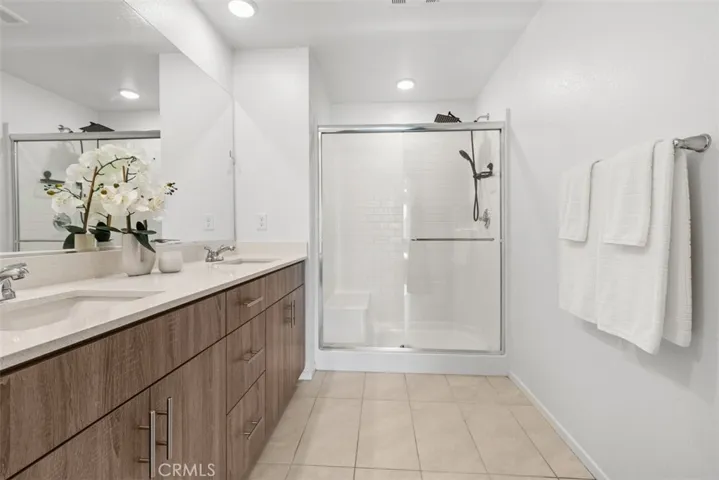 A connected en-suite bathroom with dual sinks, a walk-in shower, and elegant finishes.