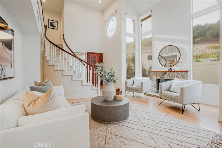 The entertainers living room is highlighted by the warm fireplace, light wood-style floors, recessed lighting, and views of the resort-like backyard.