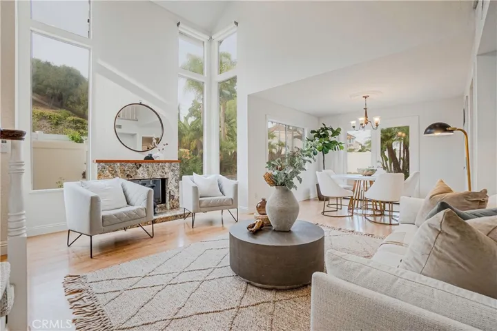 The entertainers living room is highlighted by the warm fireplace, light wood-style floors, recessed lighting, and views of the resort-like backyard.