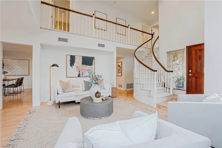 The entertainers living room is highlighted by the warm fireplace, light wood-style floors, recessed lighting, and views of the resort-like backyard.