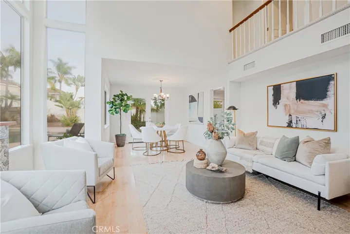 The entertainers living room is highlighted by the warm fireplace, light wood-style floors, recessed lighting, and views of the resort-like backyard.