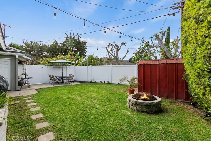 Side yard with storage shed and fenced trash enclosure in distance.
