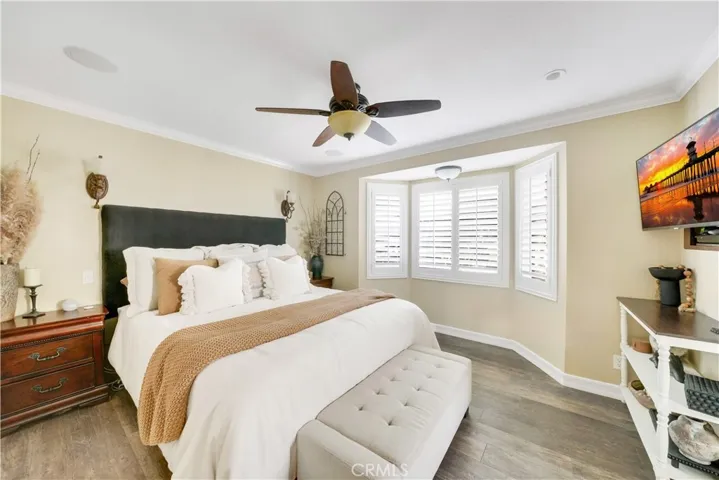 Primary bedroom with bay window, recessed lighting, crown molding, beautiful laminate flooring, wired for sound speakers in ceiling, wall sconces.