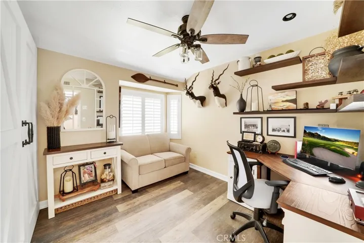 Bedroom one, currently being utilized as an office. Floating shelves not included in sale.  Bay window with plantation shutters, recessed lighting, gorgeous laminate wood flooring