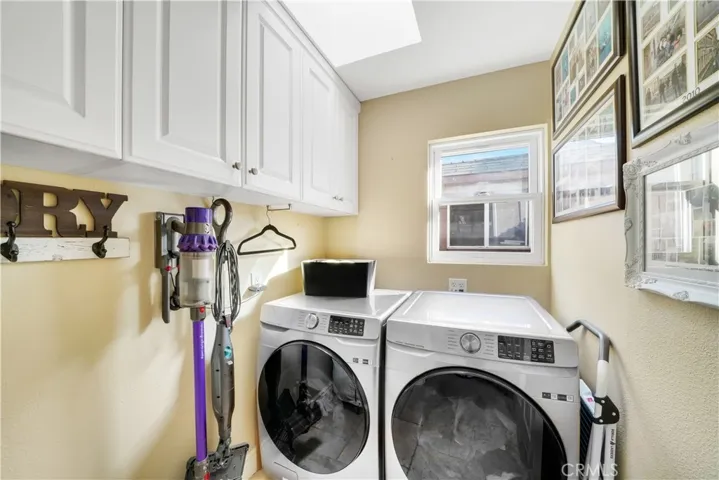 Inside laundry room with window and skylight. Cabinets.