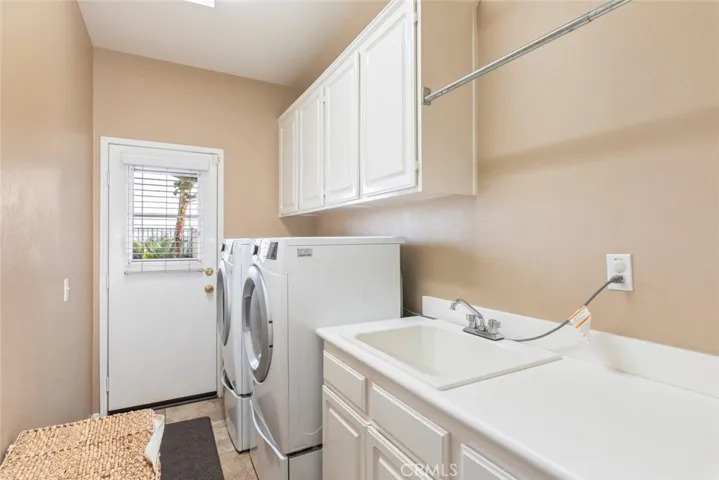 A bright and functional laundry room with cabinetry, a utility sink, for convenience.