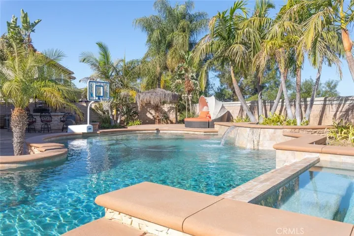 
 Resort-style pool and spa with tropical landscaping, waterfalls, and a relaxing lounge area for a vacation-like retreat at home.