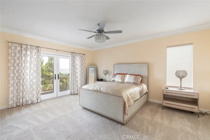 A luxurious primary bedroom with  French doors, views, and bright ambiance.