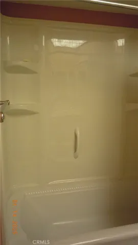 Tub enclosure in guest bath with shelving.