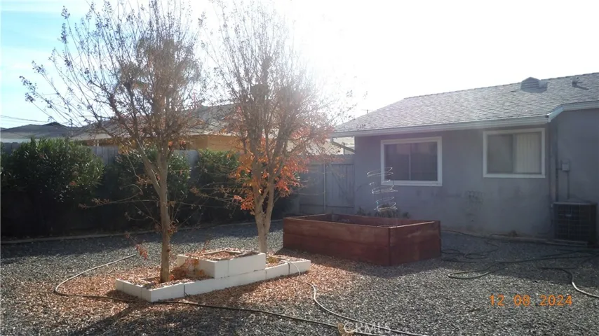 The back yard also has a side area, with trees and a raised planter bed.