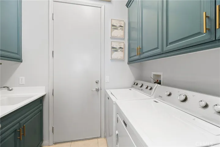 large laundry room wih Maytag washer and dryer, deep utility sink and lots of cabinets for storage. Exits to the 2 car attached gaarge.
