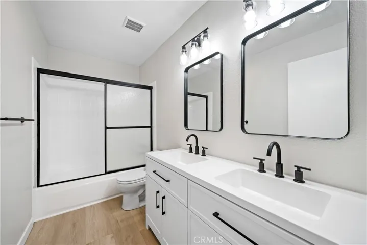 There is a remodeled full hallway bathroom with a shower/tub, dual vanity sinks, matte black finishes, light fixtures and laminate floors!
