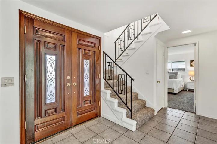 Double Entry Doors with Beveled Glass Open to a Tiled Foyer