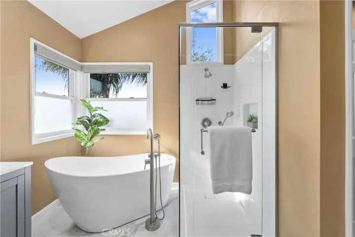 Sleek soaking tub and glass enclosed shower with dual showerheads