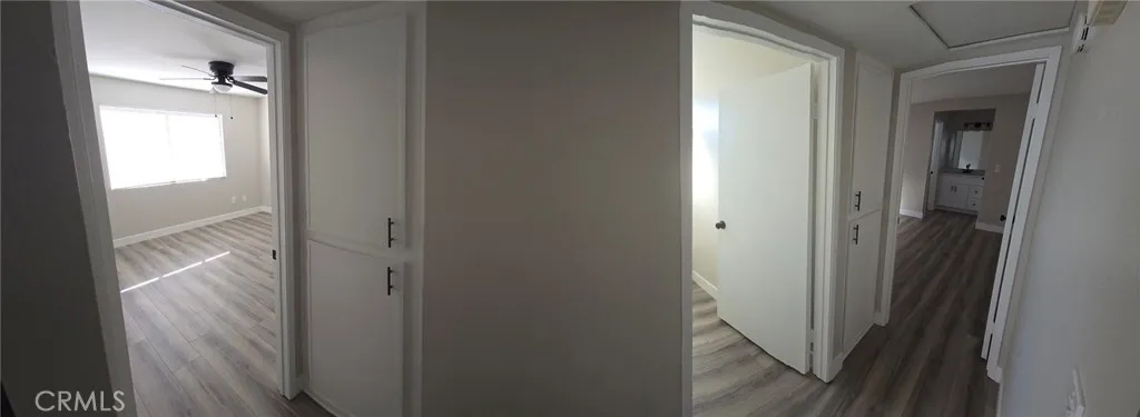 View of Hallway from Large Bedroom on left, two sets of linen cabinets, Hall Bathroom and Primary Bedroom entrance on right.