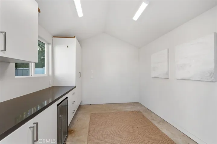 Shed in backyard that is fully finished with lighting and wine fridge.