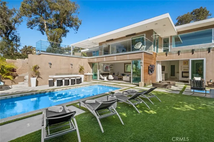 Solar power with two Tesla batteries, an attached street-level two-car garage, and a main-level secondary primary suite with a fireplace and an ocean-view balcony overlooking the backyard are also featured.