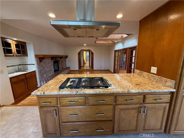 View from kitchen into family room. Six burner cooktop with range hood