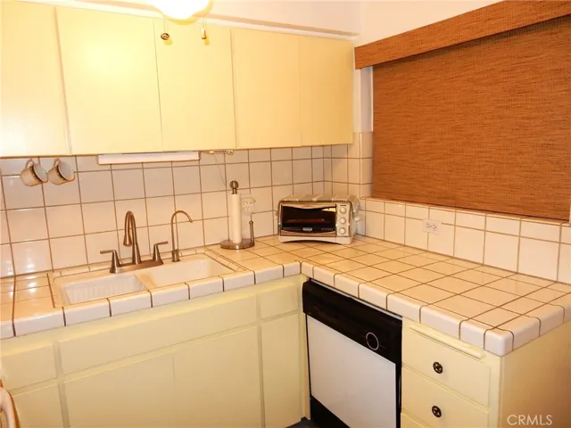 Kitchen with tile counters and dishwasher.