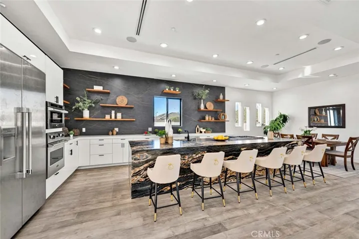 Chef's dream kitchen with eat-in banquet-size formal dining room, boasts huge leathered granite center island w/seating, Quartz countertops, 2 sinks, chic floating shelving, white gloss Thermofoil self-closing cabinetry, and stainless Viking & Thermador appliances. Coffered ceiling with recessed lighting