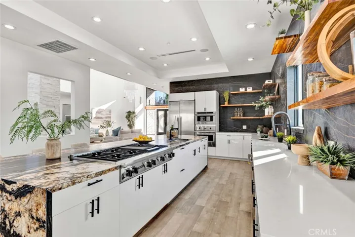  Chef's paradise kitchen with eat-in banquet-size formal dining room, boasts huge leathered granite center island w/seating, Quartz countertops, 2 sinks, chic floating shelving, white gloss Thermofoil self-closing cabinetry, and stainless Viking & Thermador appliances. Coffered ceiling with recessed lighting