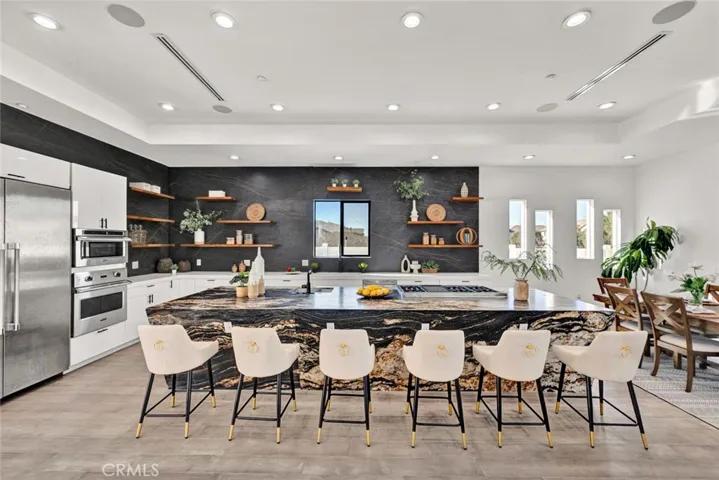 Unbelievable kitchen with eat-in banquet-size formal dining room, boasts huge leathered granite center island w/seating, Quartz countertops, 2 sinks, chic floating shelving, white gloss Thermofoil self-closing cabinetry, and stainless Viking & Thermador appliances. Coffered ceiling with recessed lighting