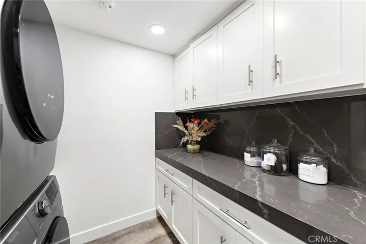 High-end tilework, luxury vinyl plank flooring, and an interior laundry room with stacked washer and dryer are also on display.