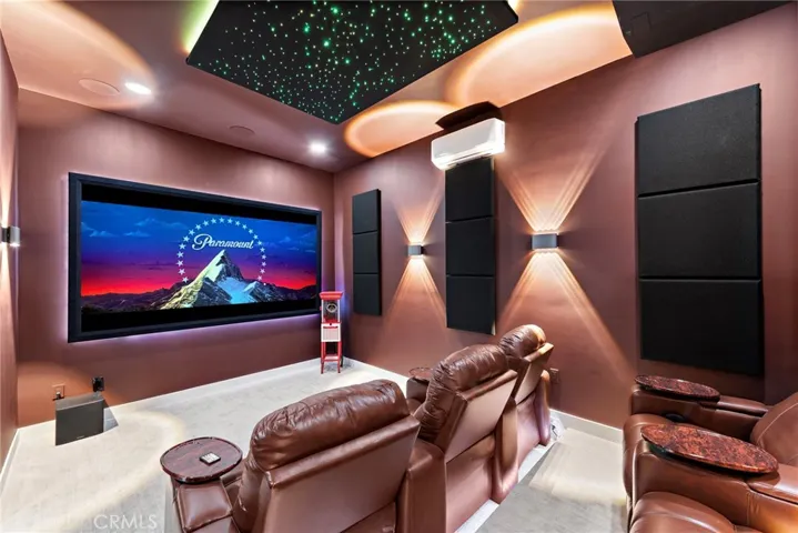 A lux home theater with large screen, high-end audio and video, acoustic panels, sumptuous seating and a ceiling with starry-night sky.