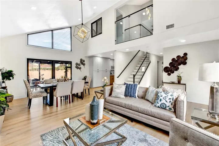 Great room style living room and dining room with soaring ceiling, marble fireplace, wood vinyl flooring, recessed lighting, dual pane windows, high transom windows, and sliders that lead to 550 square foot enclosed patio