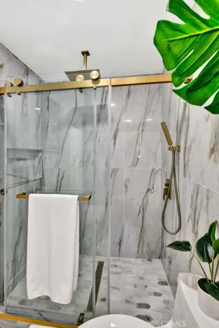 Downstairs primary suite marble walk-in shower with multiple shower heads