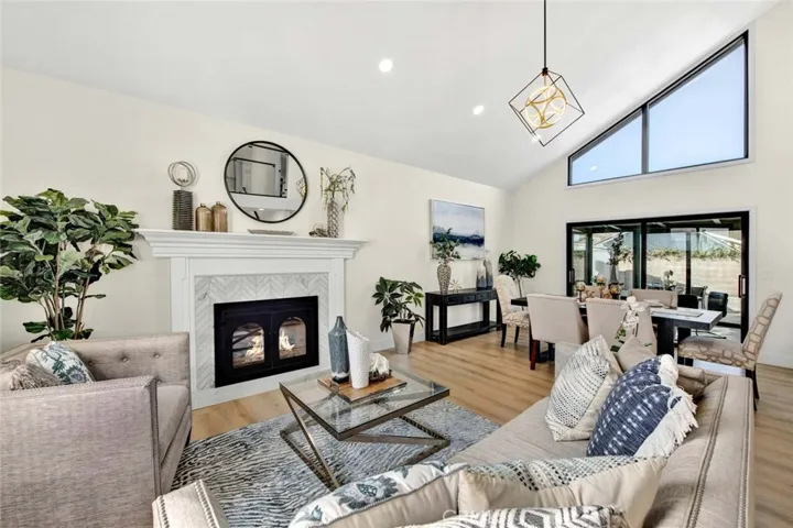 Great room style living room and dining room with soaring ceiling, marble fireplace, wood vinyl flooring, recessed lighting, dual pane windows, high transom windows, and sliders that lead to 550 square foot enclosed patio
