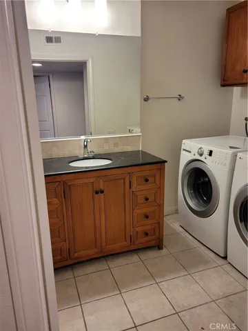 main floor bathroom #1, vanity and laundry area with tiled floors