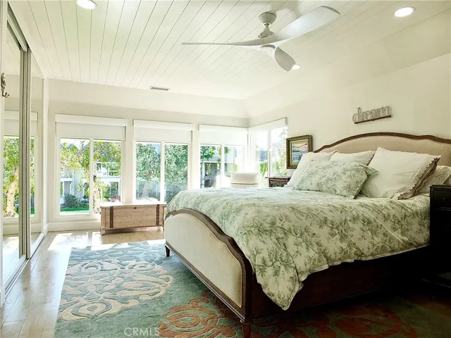 Main bedroom with wall of windows with peak a boo of Huntington Harbor.