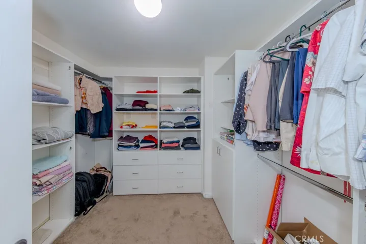 Primary bedroom walk in closet with built in storage cabinets.