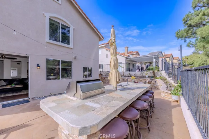 Backyard view with barbecue and bar seating and an umbrella.