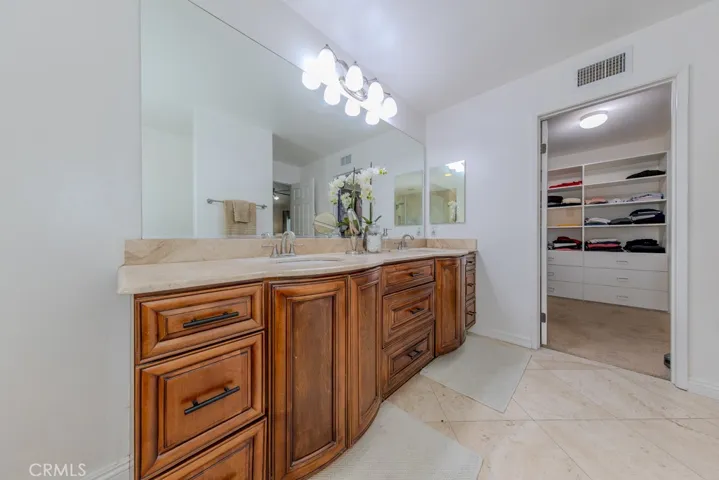 Primary bathroom featuring dual sinks and entry into the walk in closet.
