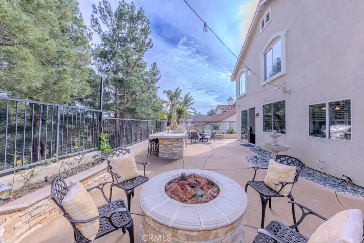 View of the backyard looking south featuring the fire pit, fountain, and barbecue and island with bar seating.