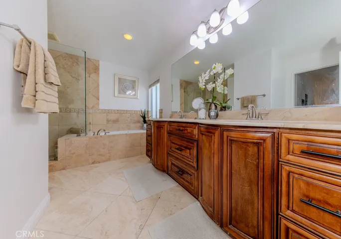Primary bathroom with dual sinks, walk in shower, and sunken tub.
