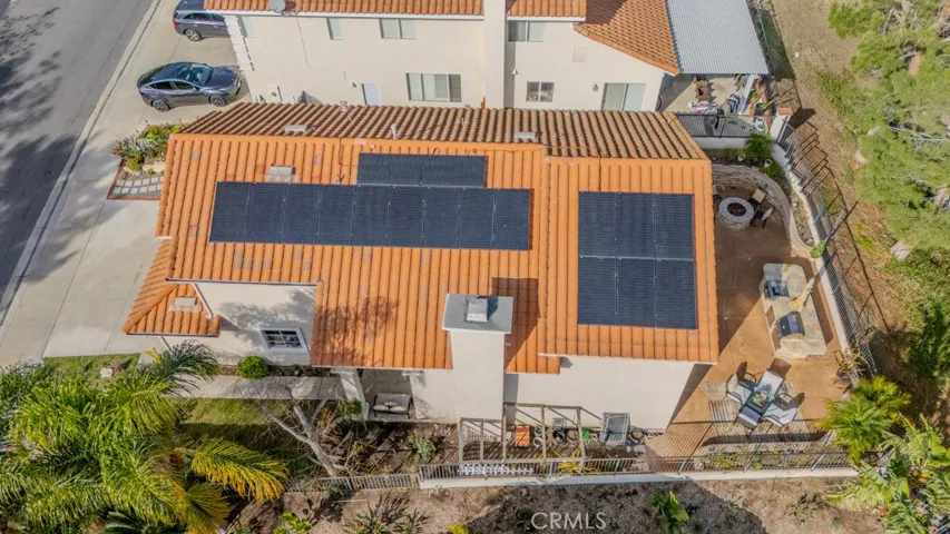 Overhead view of the home looking north with tiled roof and solar panels and south side yard.